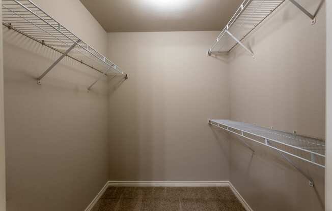 a spacious walk in closet with two shelves and a mirrored wall with two hanging racks