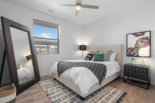 A bedroom with a large bed, a mirror, and a ceiling fan.