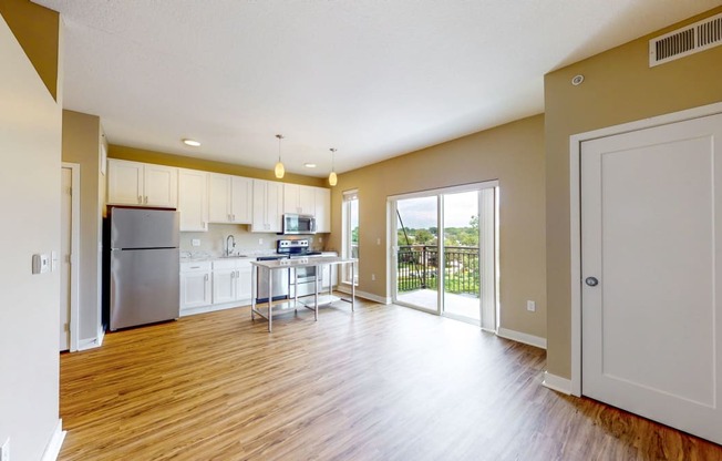 an open living room and kitchen with a door to a balcony