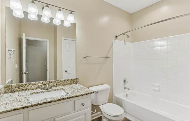 A white bathroom with a marble countertop and a white toilet.