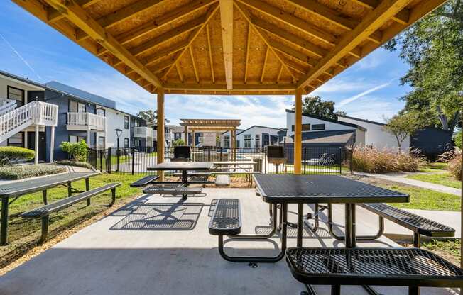two picnic tables and benches under a pavilion at an apartment complex