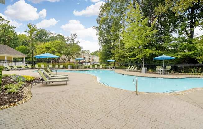 a swimming pool with benches and umbrellas and trees