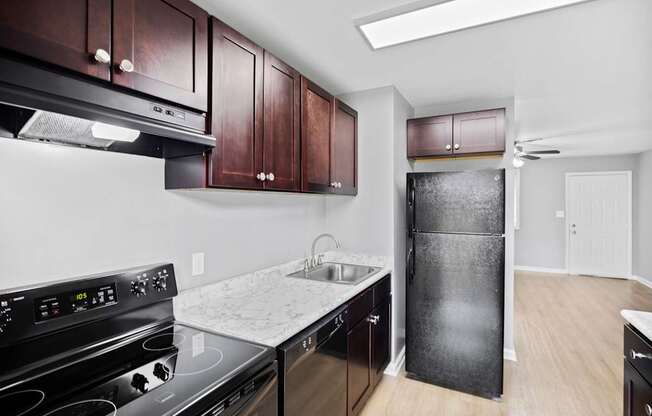 A kitchen with a black stove top oven and black fridge.
