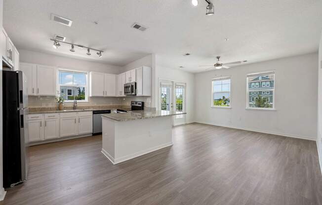 A spacious kitchen with white cabinets and a black refrigerator.