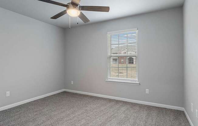 A room with a ceiling fan and a window with blinds.