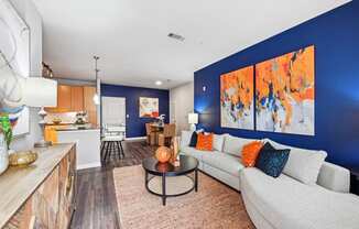 Spacious living room with blue accent wall and contemporary furniture at The Grand at Upper Kirby apartments in Houston, TX