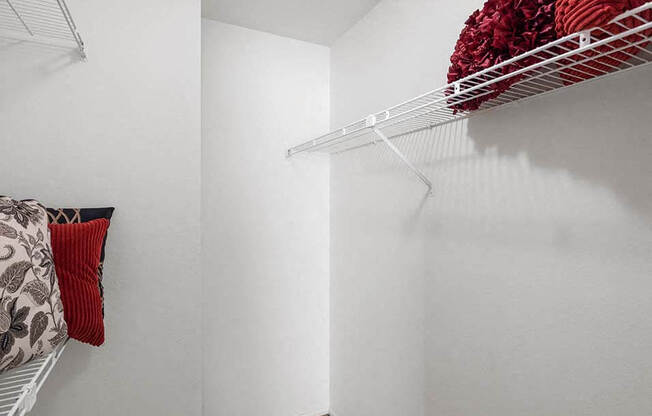 a walk in closet with a white wall and a wire rack on the wall