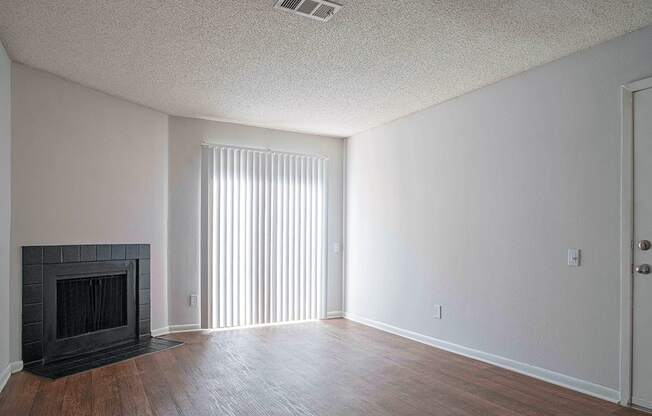 an empty living room with a fireplace and wood flooring