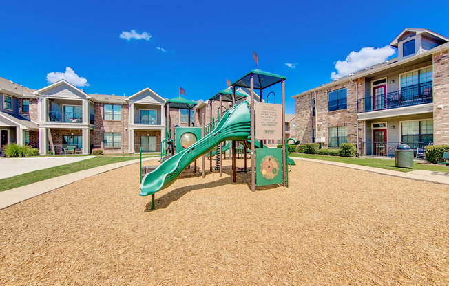 View of Playground, Showing Building Exteriors and Adjacent Sand Volleyball Court at Enclave on Golden Triangle Apartments