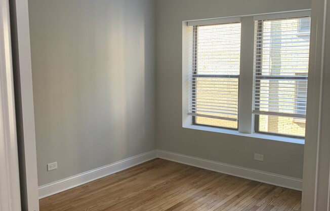 an empty room with a window and a hard wood floor