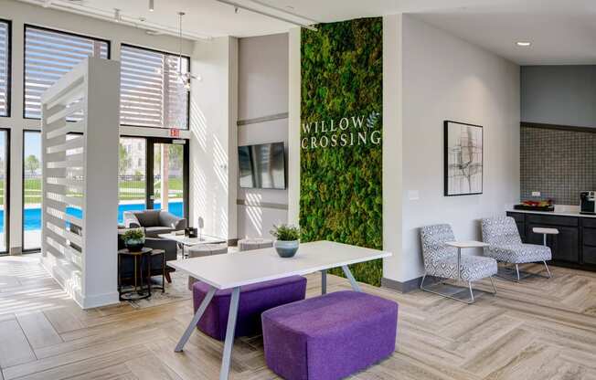 a living wall with a white table and purple chairs in a room with a pool