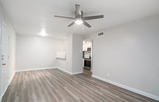 a spacious living room with a ceiling fan and hardwood floors