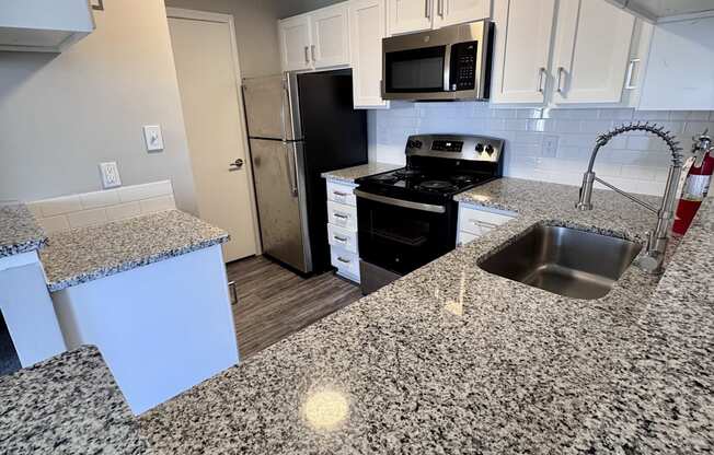 A kitchen with granite countertops and white cabinets.