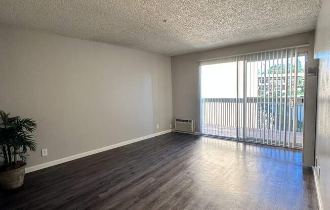 an empty living room with wood flooring and a balcony