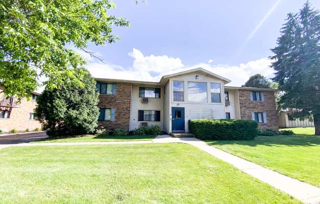 the view of an apartment building with a lawn and sidewalk in front of it