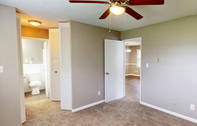 A room with a ceiling fan and carpeted floor.