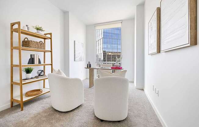 A white chair sits in a room with a wooden shelf and a window.