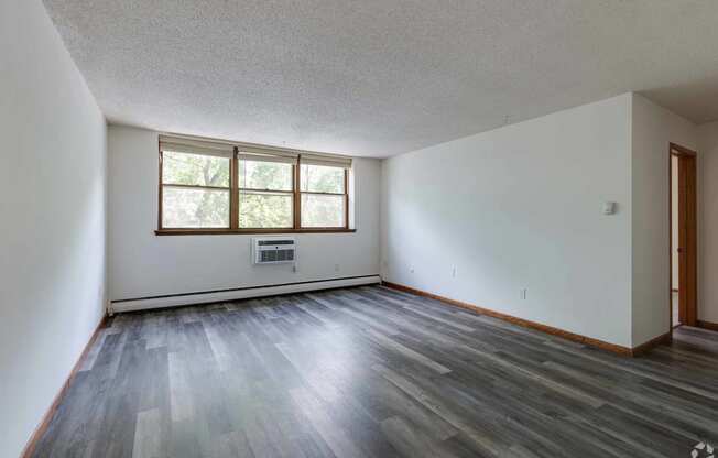 an empty living room with hardwood floors and a window