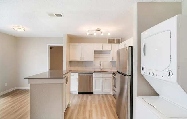 a kitchen with white cabinets and stainless steel appliances and a washer and dryer