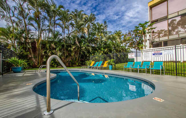 a swimming pool at a hotel with palm trees at Palms of Kilani Apartments, Wahiawa, 96786