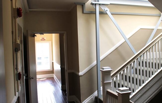 Pasadena Brookmore apartments stairwell with carpeted stairs, dual tone walls in dark and light tan with white trim, and dark wood inspired flooring