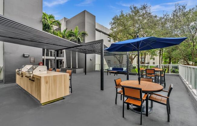 A patio with a table and chairs and a blue umbrella.