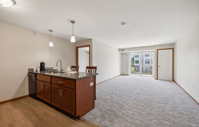 an empty living room with a kitchen and a door to a patio