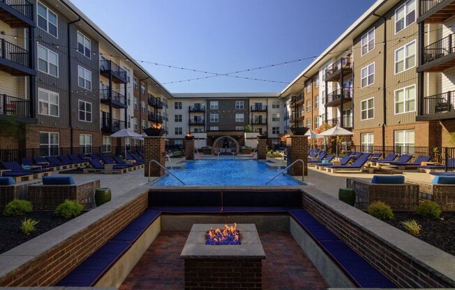 an outdoor pool with a fire pit in front of an apartment building