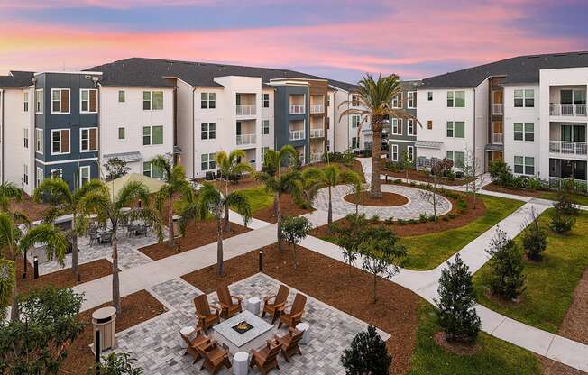 an aerial view of an outdoor dining area with a firepit in front of an apartment complex