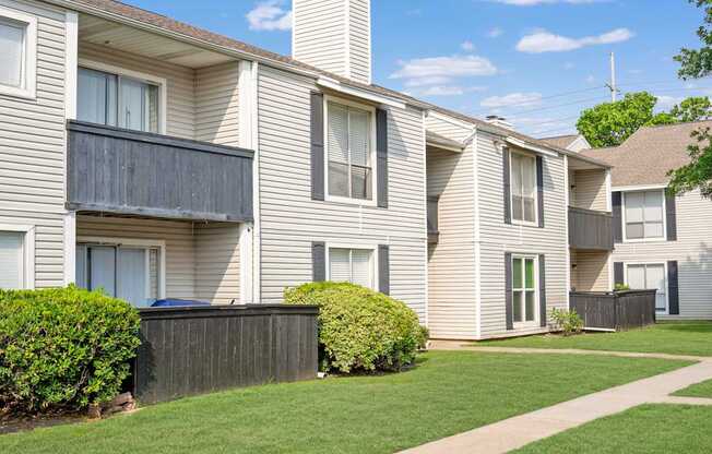 A row of beige townhouses with green lawns in front.