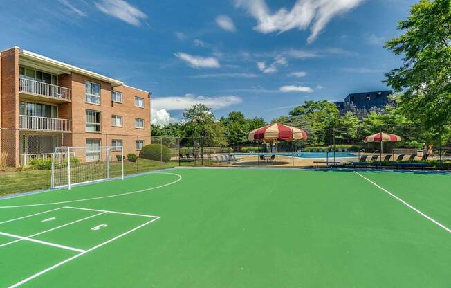 A tennis court is surrounded by apartment buildings.