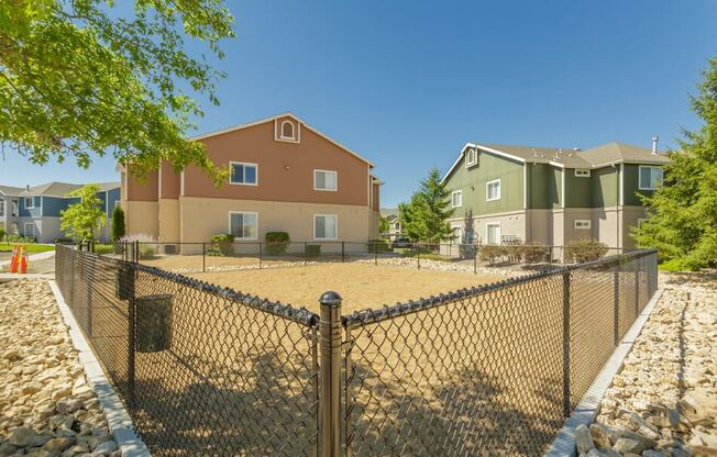 a fenced in area with apartments behind a chain link fence