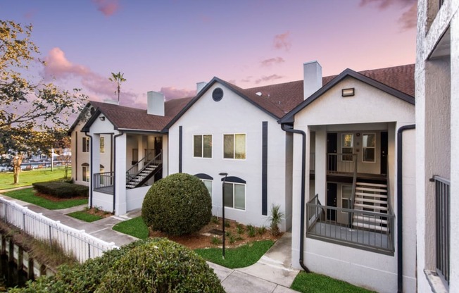 a group of white houses with a sidewalk and grass