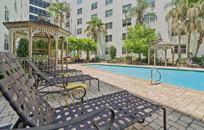 A pool area with black chairs and a gazebo.