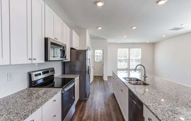 North Charleston, SC Townhomes Near Tanger Outlets - Highland Townhomes - Kitchen with Hardwood Floor, Stainless Steel Appliances, Granite Countertops, and White Cabinetry.