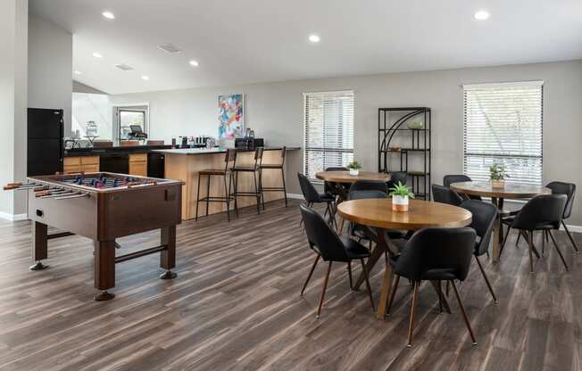 a community room with a pool table and tables with chairs