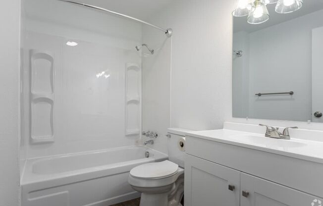 Full bathroom with faux wood flooring, a white vanity sink with under cabinet storage, mirror, toilet, and shower. at Talavera, Boise, Idaho