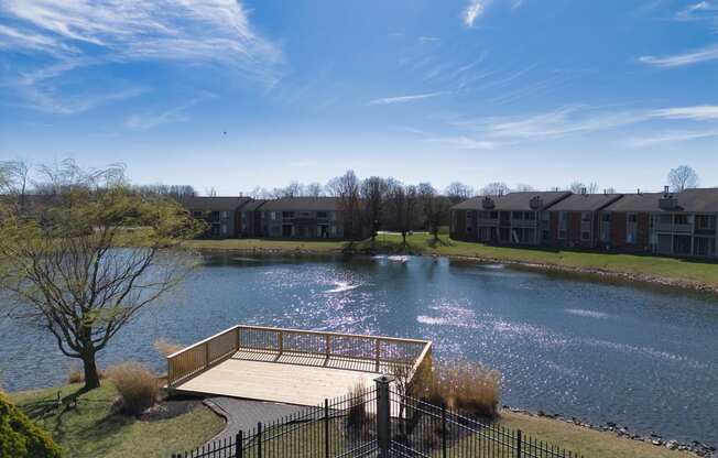 the view of a pond with a bridge in front of an apartment building