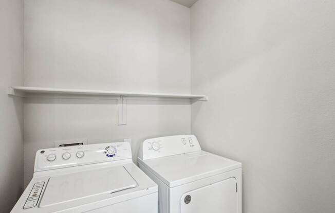 Two white front loading washing machines in a small laundry room.