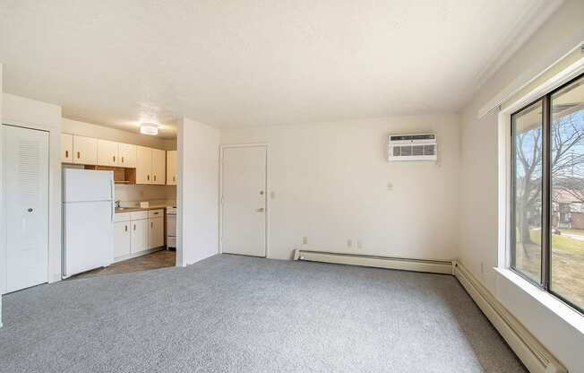 A spacious living room with a carpeted floor and a large window at Seville Apartments, Michigan
