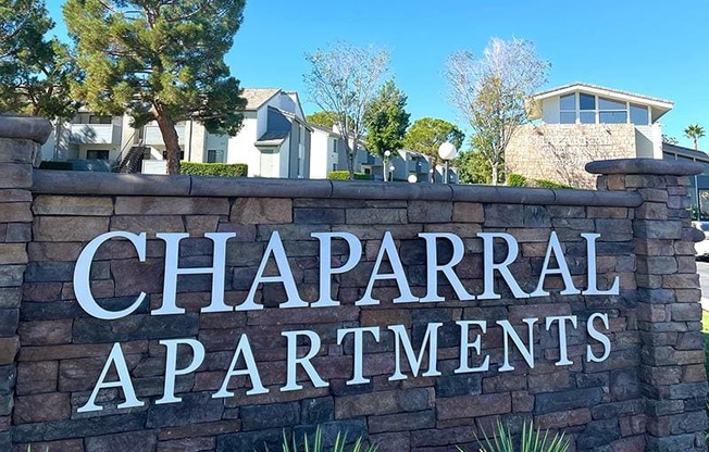 A sign that says Chaparral Apartments in front of some houses.
