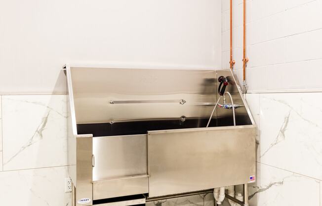 a large stainless steel sink in a kitchen with white tiles