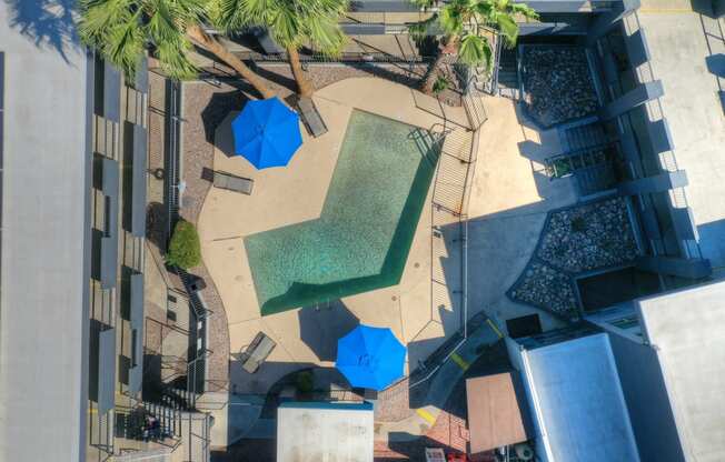 a view of the pool from above of a hotel courtyard with umbrellas