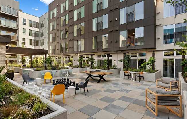 A courtyard with a checkerboard patterned floor and a variety of chairs and tables.