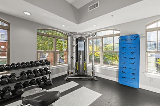 A gym with a row of dumbbells and a blue mat with footprints on it.