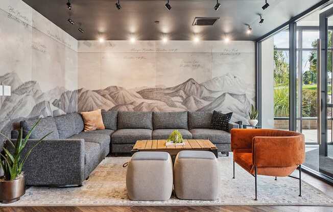 A living room with a grey sofa, a wooden coffee table, and a large mural on the wall.
