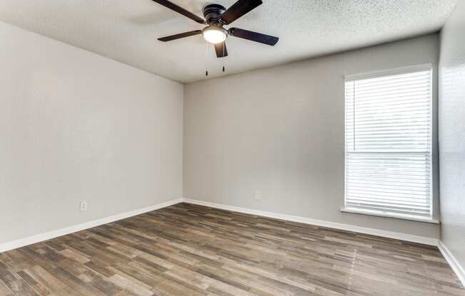 an empty living room with a ceiling fan and a window