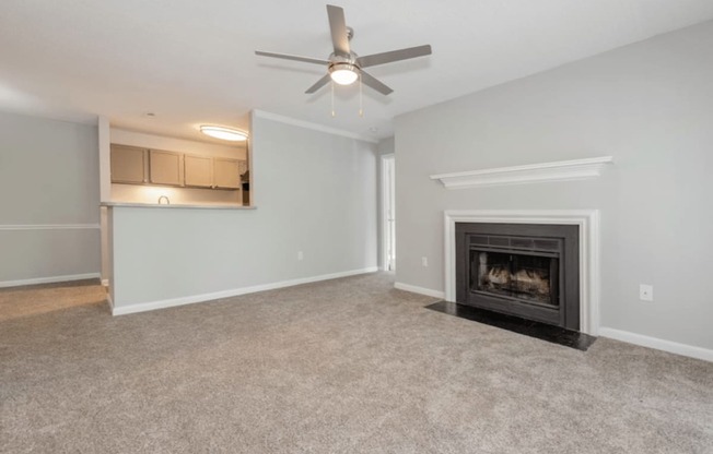 A living room with a fireplace and a ceiling fan.