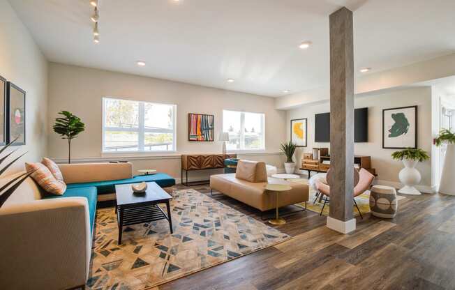 Living Room with Wood Inspired Floor, Tan Sofas, Open Windows, Pillar, Flat Screen Television Mounted on Wall