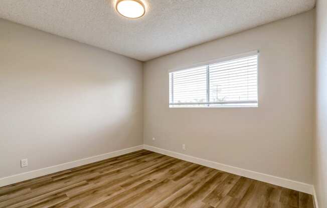 an empty room with wood floors and a window